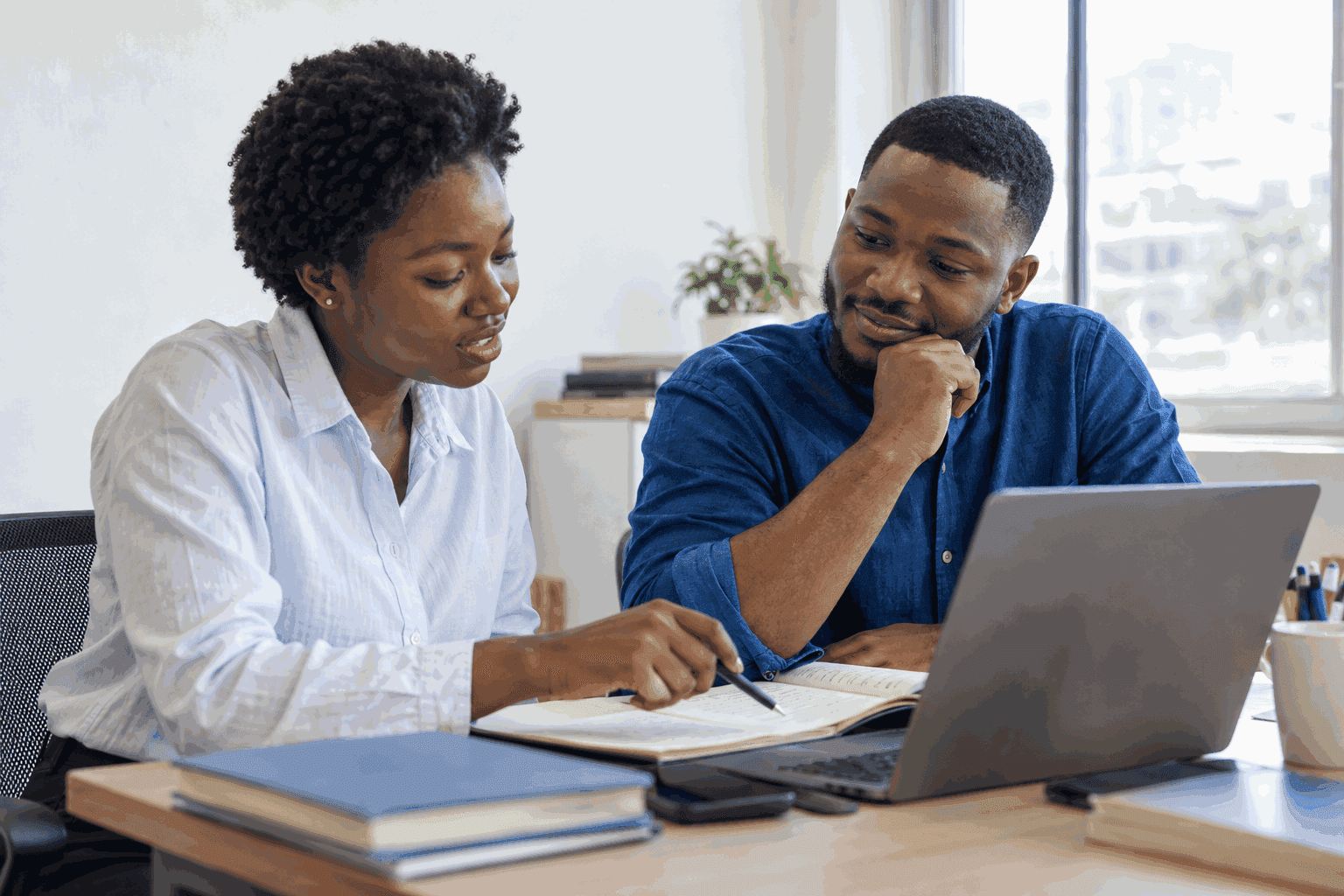 Two graduates reviewing strategic notes together at a laptop
